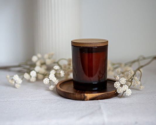 geurkaars in amberglas met houten deksel op houten schaaltje